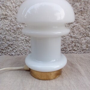 May include: White ceramic table lamp with a mushroom-shaped shade and a gold base.