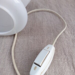 May include: A white lamp with a cord and an inline on/off switch. The switch is a rocker style with a white plastic casing.