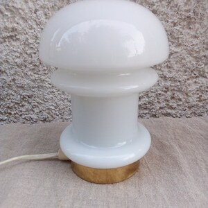 May include: A white glass table lamp with a mushroom-shaped shade and a gold base.