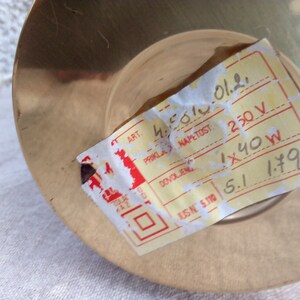 May include: A yellow label with black text on a brass base. The label reads "ART. 4501012. PRIKLA NAPETOST: 250 V DOVOLJENG 1x40W USN 5.110 5.1 1.79".