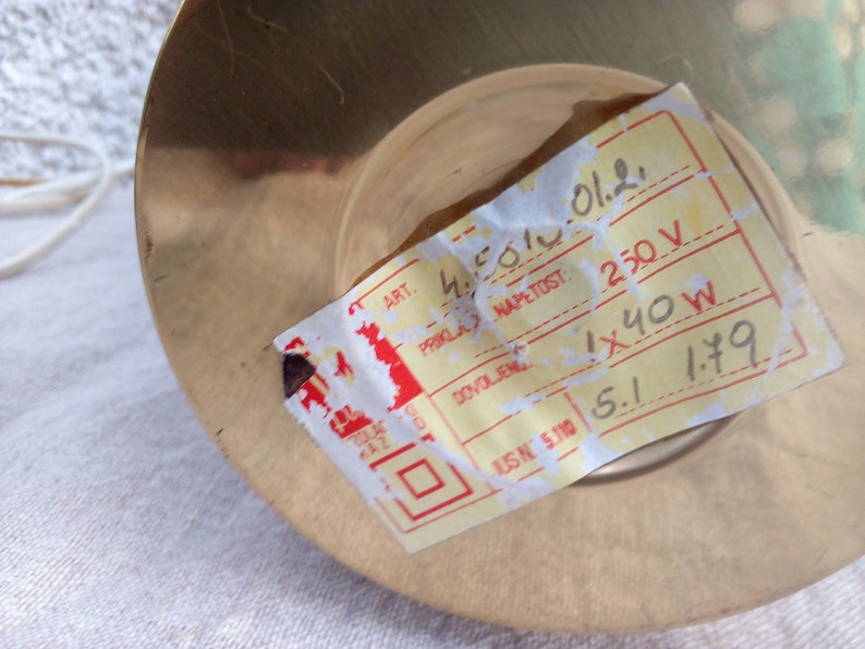 May include: A yellow label with black text on a brass base. The label reads "ART. 4501012. PRIKLA NAPETOST: 250 V DOVOLJENG 1x40W USN 5.110 5.1 1.79".