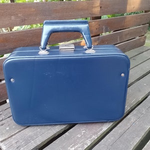 Può includere: Una valigia vintage blu scuro con maniglia e serratura argentate.