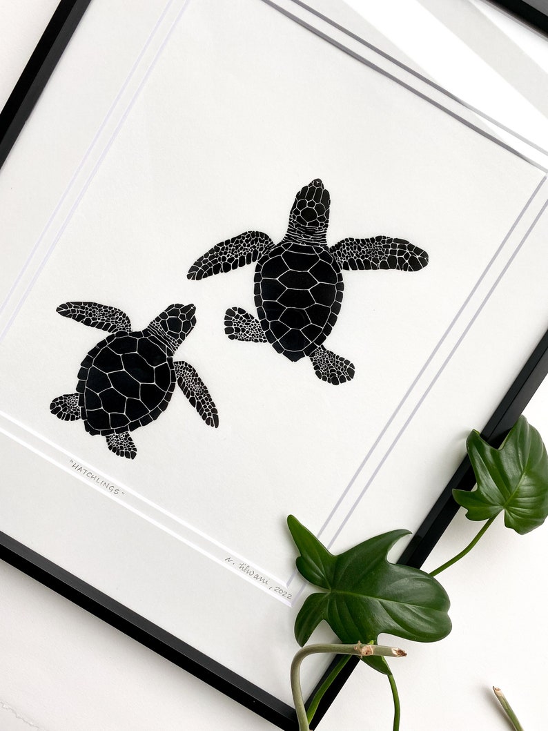 Puede incluir: L&aacute;mina art&iacute;stica enmarcada en blanco y negro con una ilustraci&oacute;n de dos tortugas marinas. Las tortugas est&aacute;n representadas en una ilustraci&oacute;n detallada y estilizada, con la palabra "Hatchlings" impresa en la parte inferior. La obra est&aacute; firmada y fechada.