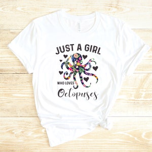 Puede incluir: Camiseta blanca con el texto "Just a girl who loves Octopuses" en negro. Un pulpo floral con contornos negros est&aacute; centrado en la camiseta.