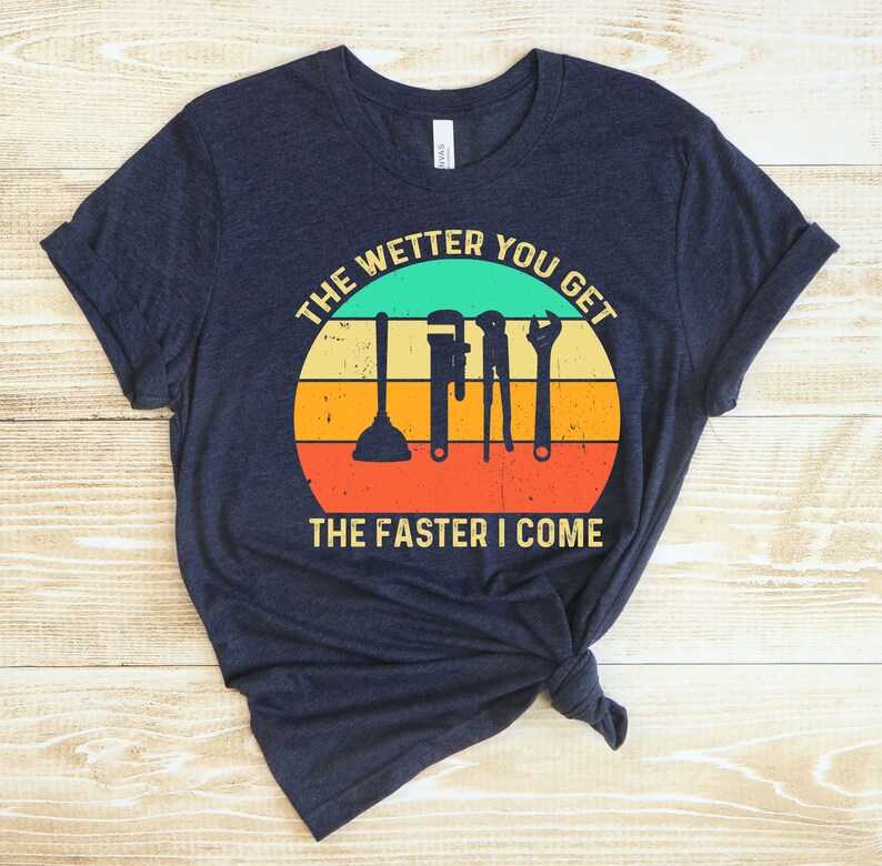 Puede incluir: Camiseta azul marino con un dise&ntilde;o retro de puesta de sol. El dise&ntilde;o presenta herramientas de fontaner&iacute;a y el texto "THE WETTER YOU GET THE FASTER I COME". La camiseta est&aacute; hecha de un material suave y c&oacute;modo.