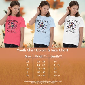 Puede incluir: Tabla de tallas de camiseta para j&oacute;venes con medidas en pulgadas. La tabla muestra el ancho y la longitud de la camiseta en pulgadas para las tallas XS, S, M, L y XL. La camiseta est&aacute; disponible en rosa, azul claro y blanco.