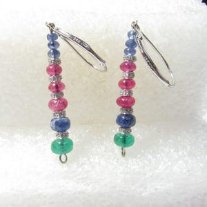 May include: A pair of drop earrings featuring 14k white gold lever back hooks. Each earring consists of a vertical arrangement of two blue sapphire beads, two pink ruby beads, one blue sapphire bead, and one green emerald bead, separated by small silver-toned spacers.