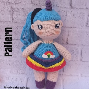 May include: A handmade crochet unicorn doll with blue hair and a horn. The doll wears a blue dress with a rainbow and cloud design. The text "Pattern" is visible on the left side of the image, and the text "@foriveahappiness" is at the bottom.