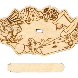 May include: A wooden cutout of an Alice in Wonderland themed design. The design features a pocket watch, a teacup, a playing card, a rose, a top hat, and gears. The cutout is attached to a wooden stand.
