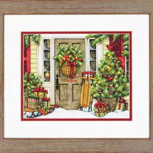 May include: A red door with a wreath and a Christmas tree decorated with baubles and a red robin. There are presents wrapped in red and green paper on a sledge in front of the door. The door has a sign that says "Thompson".