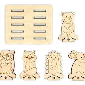 May include: Wooden craft kit featuring five animal shapes: an owl, fox, hedgehog, rabbit, and bear. Each shape has a slot for inserting a dowel rod, and the kit includes a wooden base with slots for holding the finished animals.