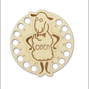 Könnte beinhalten: Eine Holzwolle Schüssel mit 15 Löchern zum Aufbewahren von Garn. Die Schüssel ist in Form eines Schafes mit dem Wort "ОВЕН" auf dem Körper.