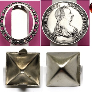 Puede incluir: Un marco ovalado de metal plateado con un borde decorativo. El marco está rodeado por una moneda de metal plateado con el texto "MARIA THERESIA D.G.REG.HUNG.BOH." La moneda está sobre una superficie rosa. También se muestran dos tachuelas piramidales de metal plateado.