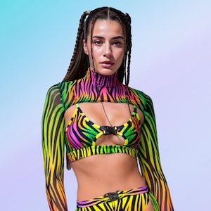 Op de afbeelding: Een opvallende outfit met zebraprint in neonkleuren. De set bestaat uit een top met hoge hals en lange mouwen, een bikinitop en een broek met hoge taille. De kleuren zijn geel, roze, groen en zwart. Met gespsluiting.