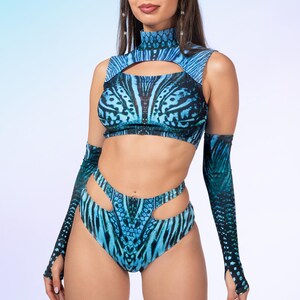 May include: A two-piece set featuring a high-neck sleeveless crop top with a chest cutout and high-waisted bottoms with side cutouts, both in a blue and black patterned print, accompanied by matching long arm sleeves with thumb holes.