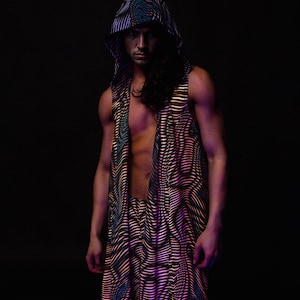 May include: A sleeveless hooded vest and matching pants with a wavy, striped pattern in shades of black, blue, and gold. The outfit is worn by a person with long, dark hair against a black background.