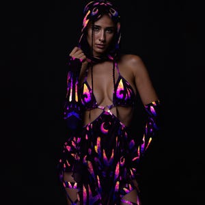 Puede incluir: Un atuendo negro con capucha, top de bikini y falda, con un diseño reflectante e iridiscente en morado, naranja y azul. El atuendo tiene un patrón único y es adecuado para un evento especial.