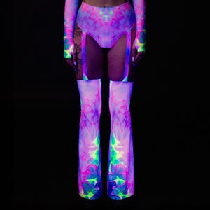 May include: A neon tie-dye outfit featuring a high-waisted bottom, long-sleeved top, and thigh-high leg warmers. The outfit is predominantly pink and purple with green and blue accents, creating a vibrant, psychedelic effect against a black background.