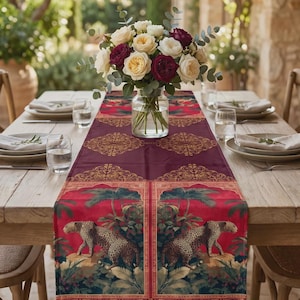 Può includere: Un lungo runner da tavola rettangolare caratterizzato da uno sfondo rosso intenso con un motivo ripetuto di leopardi in un ambiente giungla, accentuato da bordi decorativi dorati ornati e motivi floreali su un tavolo da pranzo in legno.