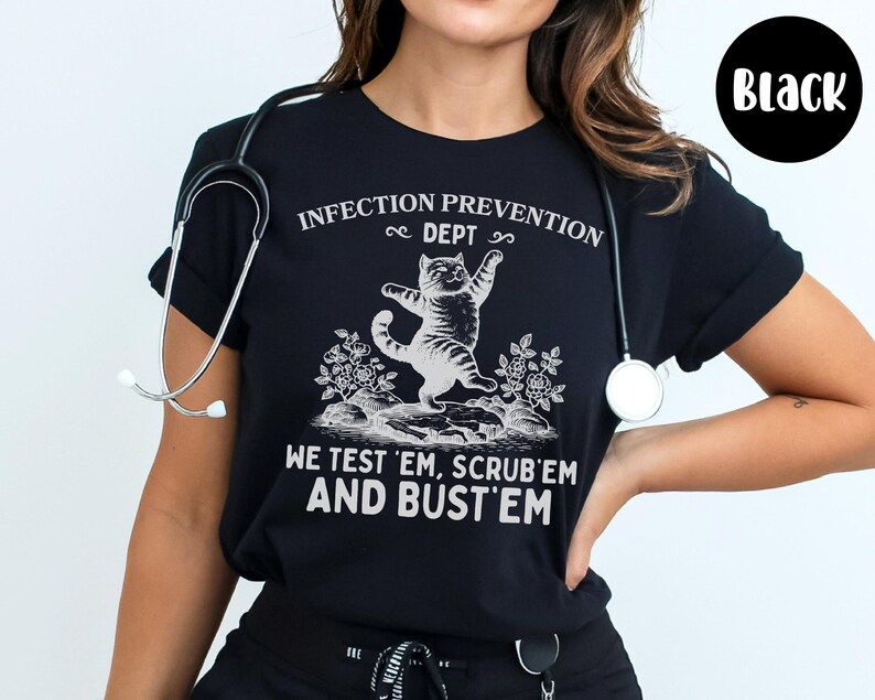 May include: Black t-shirt with a white graphic of a cat and the text "INFECTION PREVENTION DEPT, WE TEST 'EM, SCRUB 'EM AND BUST 'EM". A stethoscope is around the neck.