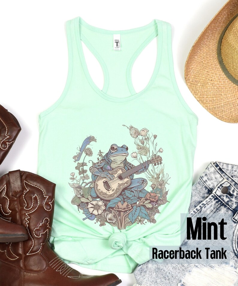 May include: Mint green racerback tank top with a graphic of a frog playing a guitar surrounded by flowers and mushrooms.