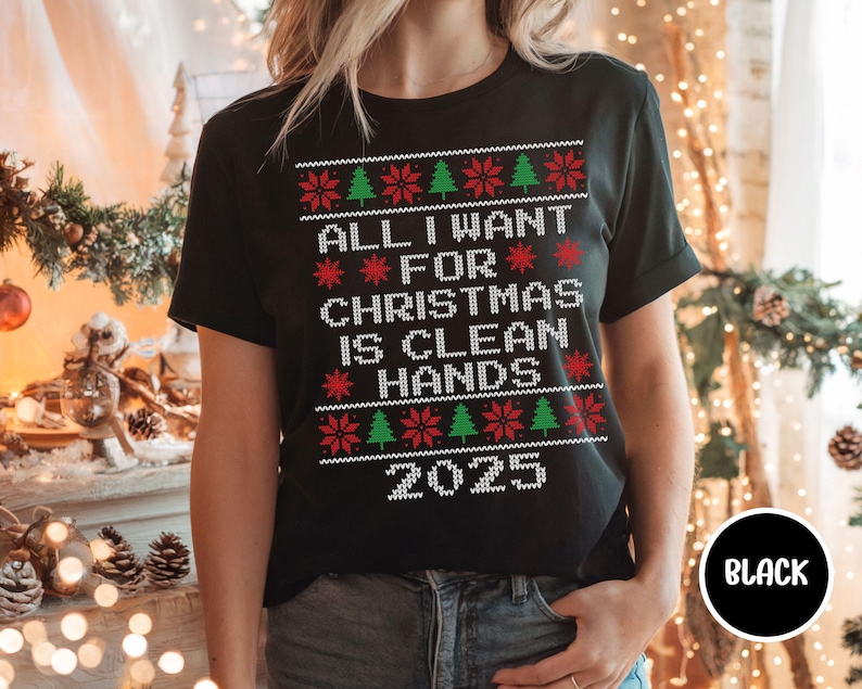 May include: Black t-shirt with a festive Christmas design. The shirt features the text "ALL I WANT FOR CHRISTMAS IS CLEAN HANDS 2025" in white, red, and green. The design includes Christmas trees and snowflakes.