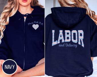 May include: Navy blue zip-up hoodie with the text "Mary Ruth R.N." and a heart on the front. The back of the hoodie displays the words "LABOR and Delivery" in a striped design. The word "NAVY" is in a circle at the bottom.