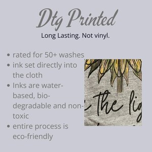 May include: A gray t-shirt with a sunflower design and the words "the light". The image also includes text stating the shirt is DTG printed, long lasting, and eco-friendly. The ink is water-based and non-toxic.