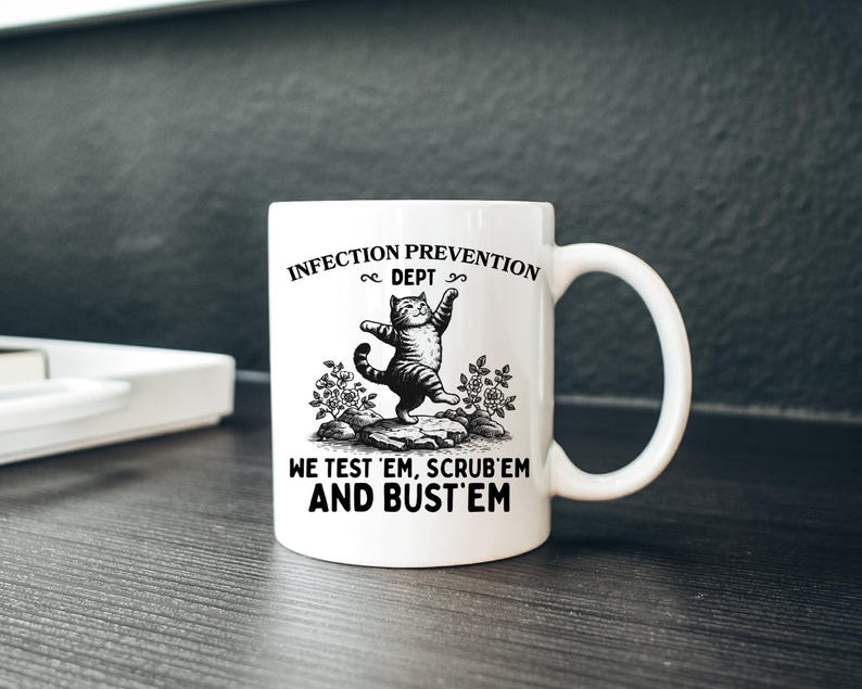 May include: White ceramic mug with a black and white illustration of a cat standing on its hind legs. The mug has the text "INFECTION PREVENTION DEPT" and "WE TEST 'EM, SCRUB 'EM AND BUST 'EM".