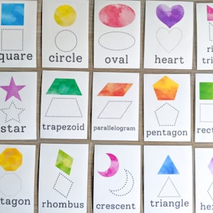 May include: A set of 16 flashcards featuring different shapes, including a square, circle, oval, heart, triangle, star, trapezoid, parallelogram, pentagon, rectangle, octagon, rhombus, crescent, and hexagon. Each card has a watercolor illustration of the shape and a dotted outline for tracing.