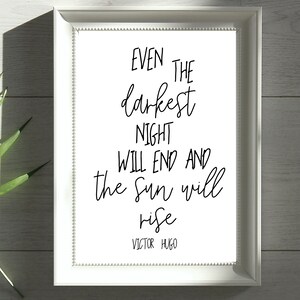 May include: A white framed print with a black and white quote that reads "Even the darkest night will end and the sun will rise" by Victor Hugo.