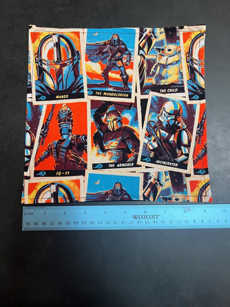 Puede incluir: Tela cuadrada con ilustraciones coloridas de personajes de una popular serie de ciencia ficci&oacute;n. Las im&aacute;genes incluyen a Mando, The Mandalorian, The Child, IG-11, The Armorer y el Incinerator. La tela mide aproximadamente 25 cm de ancho.