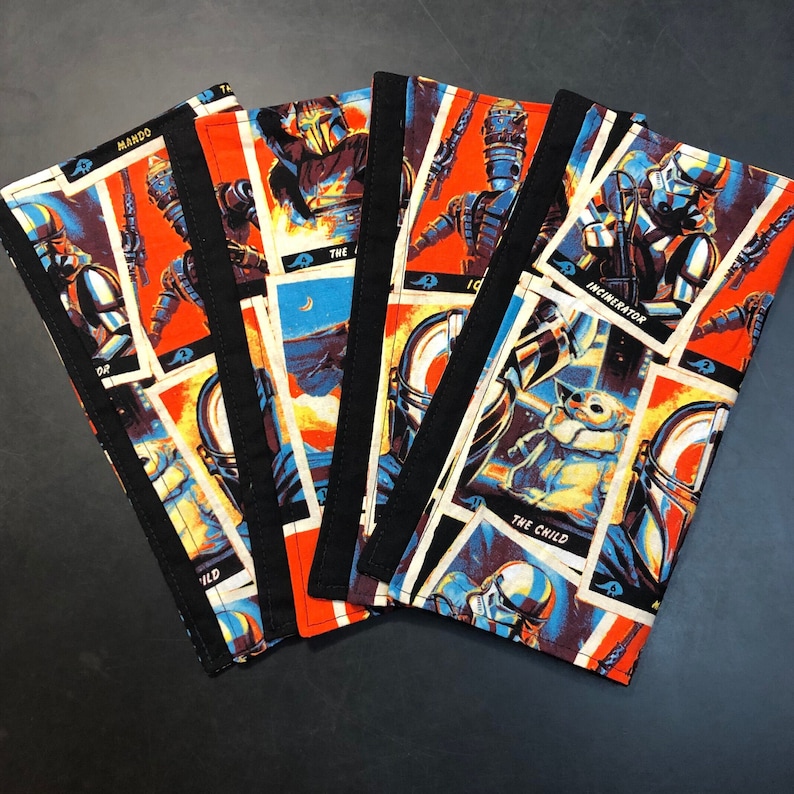 Puede incluir: Un conjunto de cinco cuadernos de tela con personajes de Star Wars en estilo c&oacute;mic. Las cubiertas tienen un fondo naranja vibrante con im&aacute;genes de personajes como The Mandalorian y The Child, con lomos negros.