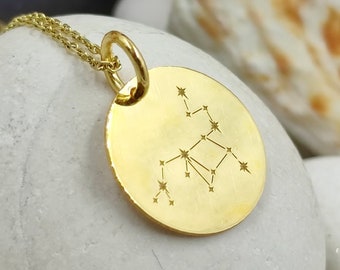 Puede incluir: Un collar de oro con un colgante redondo que representa la constelación de Virgo. El colgante está grabado con un contorno detallado de la constelación.
