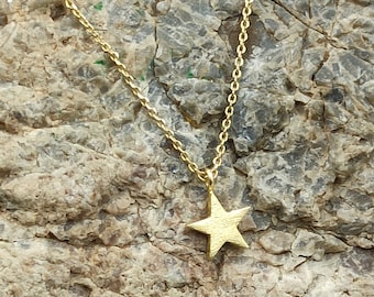 May include: A gold chain necklace with a small, five-pointed star pendant.