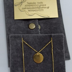 May include: A gold necklace with a round pendant in a gray velvet pouch. The pouch has a gold tag with the text "Tasioulas Vasilis ATHENSGOLD greece mail-tasioulasbill@yahoo.gr tel.6945505771"