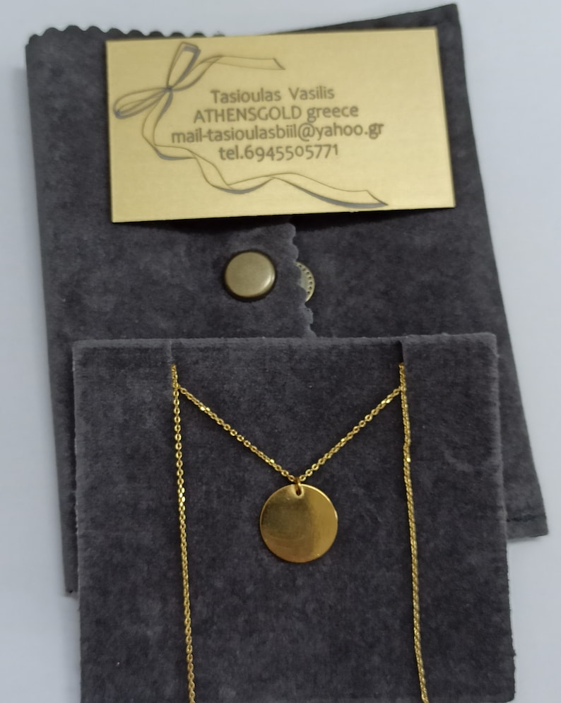 May include: A gold necklace with a round pendant in a gray velvet pouch. The pouch has a gold tag with the text "Tasioulas Vasilis ATHENSGOLD greece mail-tasioulasbill@yahoo.gr tel.6945505771"