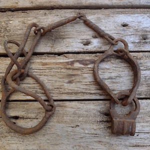 Antique leg irons with a padlock, 1600s wrought iron legcuffs, old rusty hand forged restraints, collectible 17th century shackles