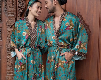 May include: A couple wearing matching blue and gold patterned robes with floral designs. The robes have a black trim and are tied at the waist.