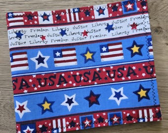 May include: A square fabric coaster featuring a patriotic pattern with red, white, and blue stripes, stars, and text. The design includes repeating words Liberty, Freedom, and Justice, along with USA printed in bold black letters on a red band.