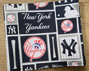 May include: A square fabric item featuring a New York Yankees print with navy blue, white, and grey panels. The design includes the team name, the interlocking NY logo, baseballs, bats, and the MLB silhouette logo with a patriotic top hat graphic.