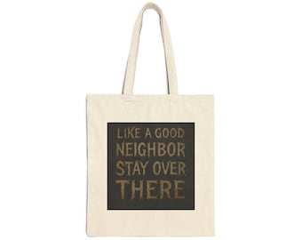 Könnte beinhalten: Cremefarbene Tragetasche mit dem Text "LIKE A GOOD NEIGHBOR STAY OVER THERE" in brauner, strukturierter Schrift auf einem dunkelbraunen Quadrat. Die Tasche hat ein schlichtes Design mit langen Henkeln.