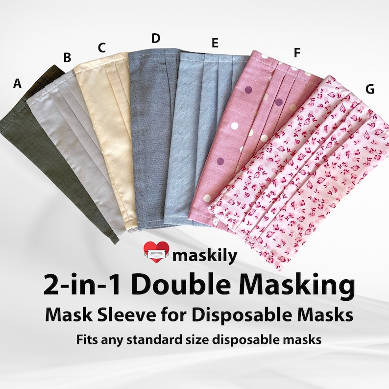May include: Seven different fabric face mask covers in various colours and patterns, including green, grey, beige, blue, pink with white polka dots, and pink with a floral pattern. The text "maskily 2-in-1 Double Masking Mask Sleeve for Disposable Masks Fits any standard size disposable masks" is below the masks.