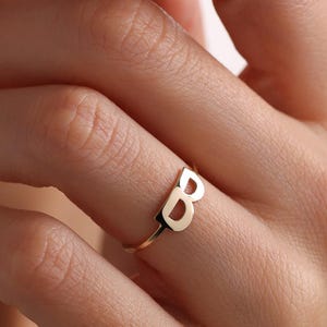 May include: A gold initial ring with the letter 'B' in a bold, modern font.