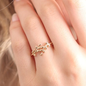 May include: A delicate gold ring featuring a design of intertwined branches with small leaves.