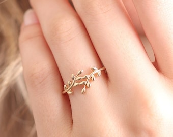 Puede incluir: Un delicado anillo de oro con un diseño de ramas entrelazadas con pequeñas hojas.