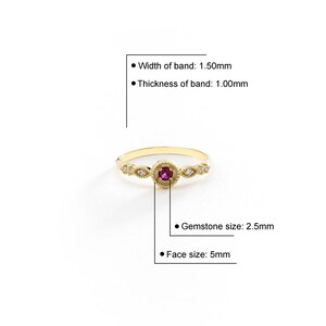 May include: A gold ring featuring a red gemstone and small white gemstones set in a delicate filigree design. The band is 1.50mm wide and 1.00mm thick. The gemstone is 2.5mm in diameter and the face of the ring is 5mm wide.