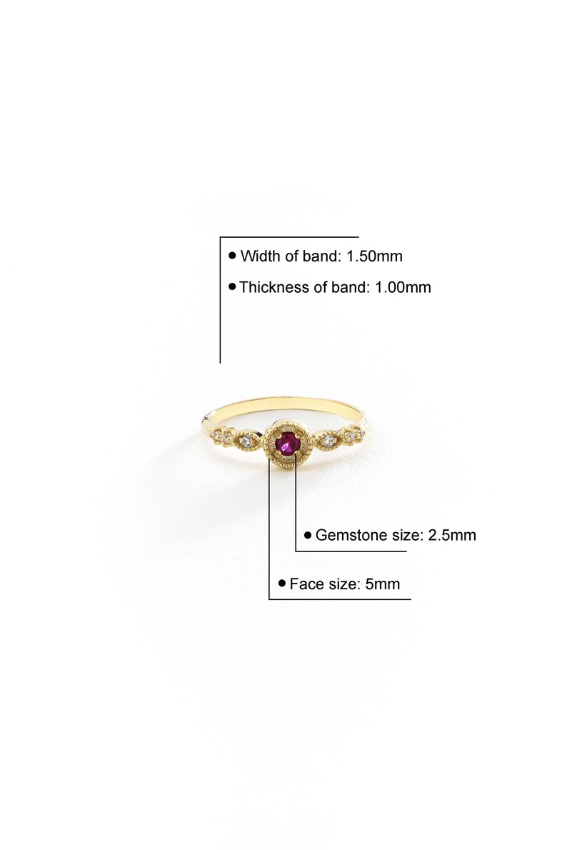 May include: A gold ring featuring a red gemstone and small white gemstones set in a delicate filigree design. The band is 1.50mm wide and 1.00mm thick. The gemstone is 2.5mm in diameter and the face of the ring is 5mm wide.
