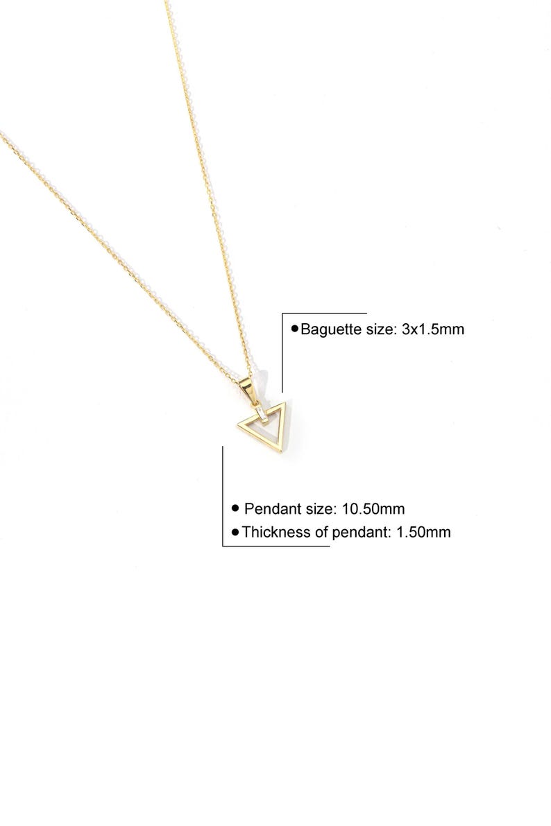Puede incluir: Un collar dorado con un colgante triangular. El colgante mide 10,50 mm de tama&ntilde;o y 1,50 mm de grosor, con una baguette de 3x1,5 mm. El collar se muestra sobre un fondo blanco.