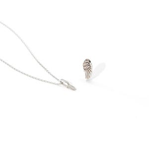May include: A silver necklace with a delicate chain and a small pendant. A matching silver wing-shaped earring is also visible, casting a shadow on the white background. The jewelry is likely made of sterling silver.